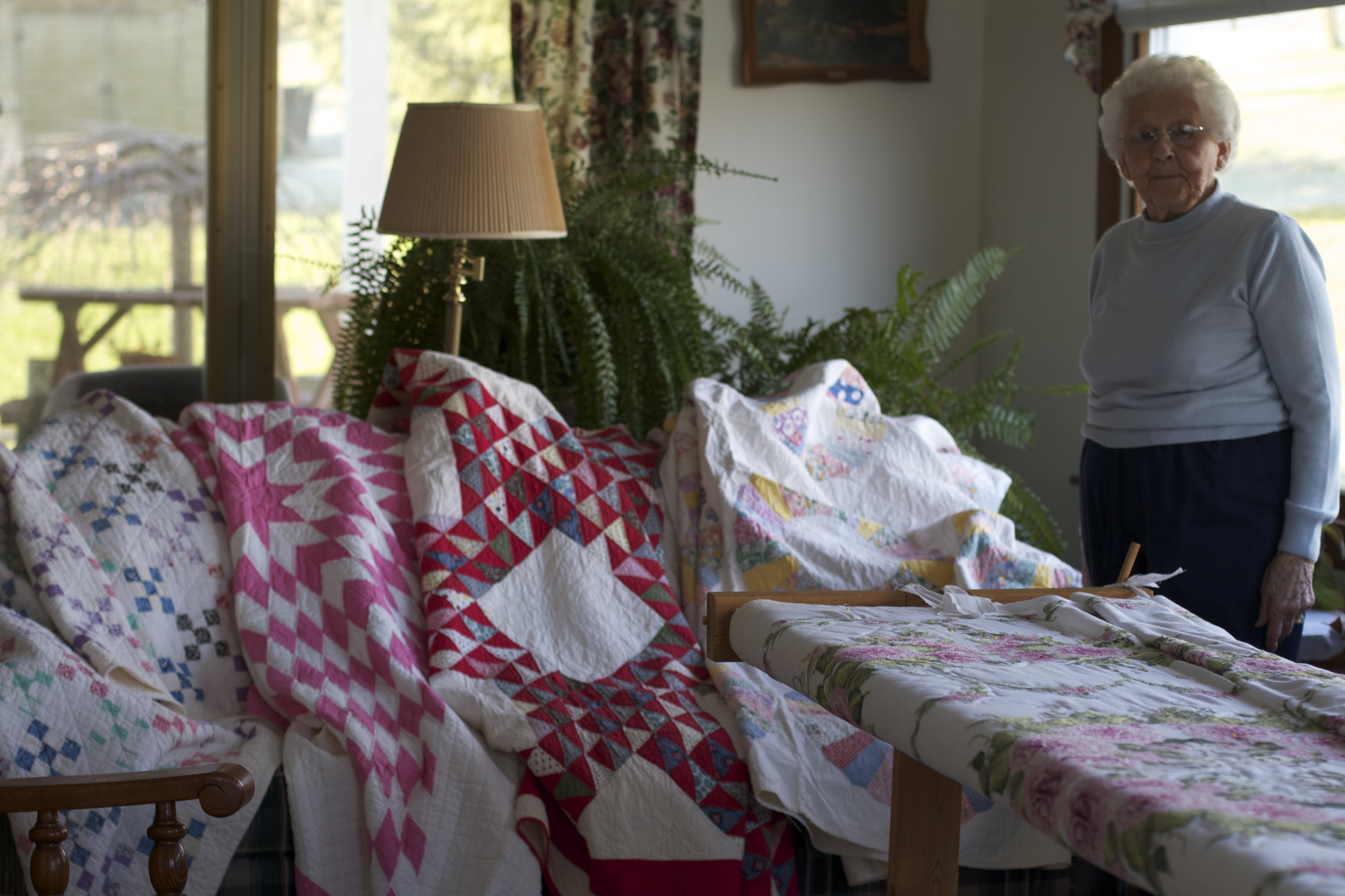 Interviewee Juanita Shockey Harris stands before her family's heirloom quilts.